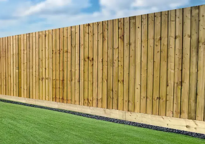 A finished run of closeboard featheredge fencing on a gravel board, alongside a lawn