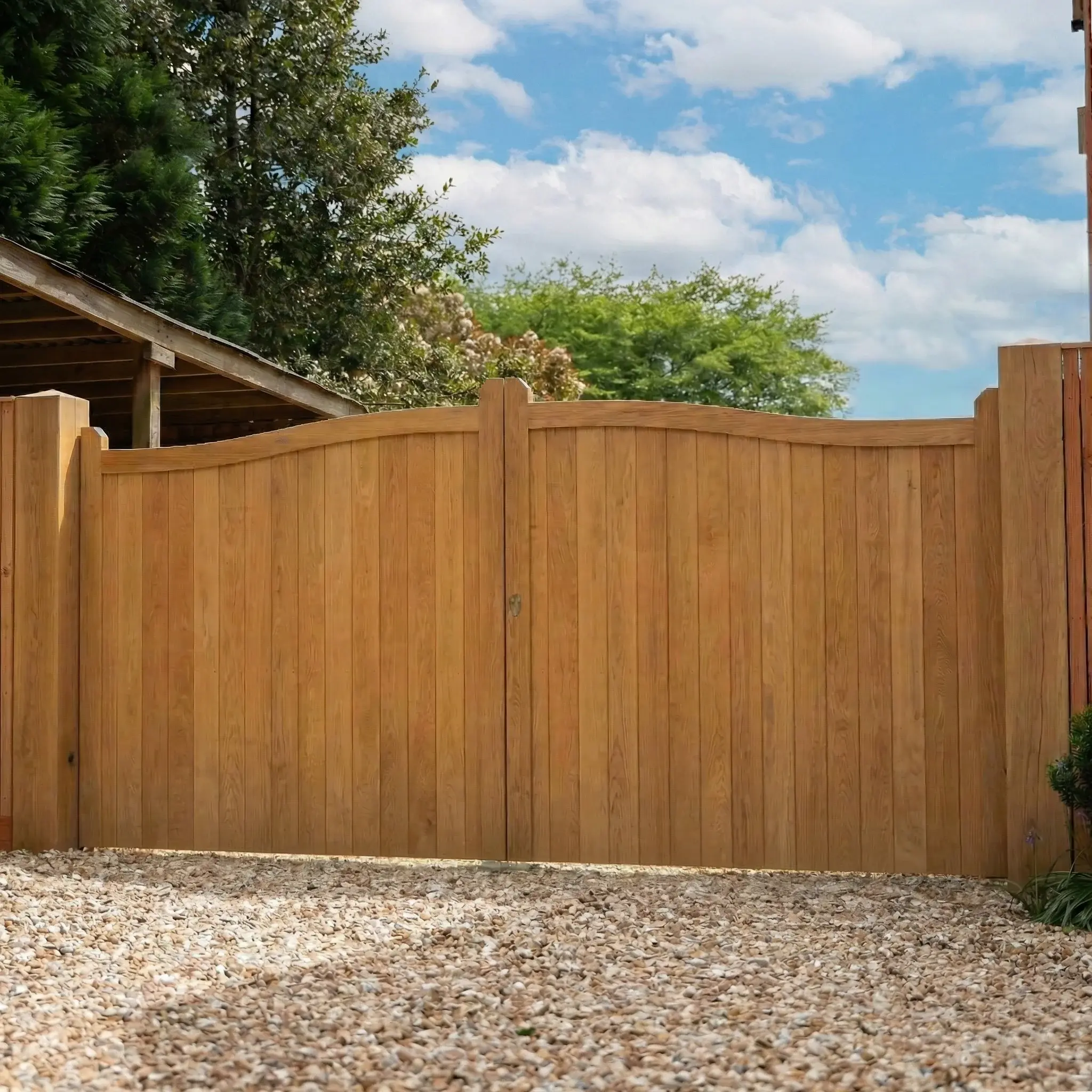 A pair of curved-top oak driveway gates hung between timber posts on a gravel drive in Beaconsfield